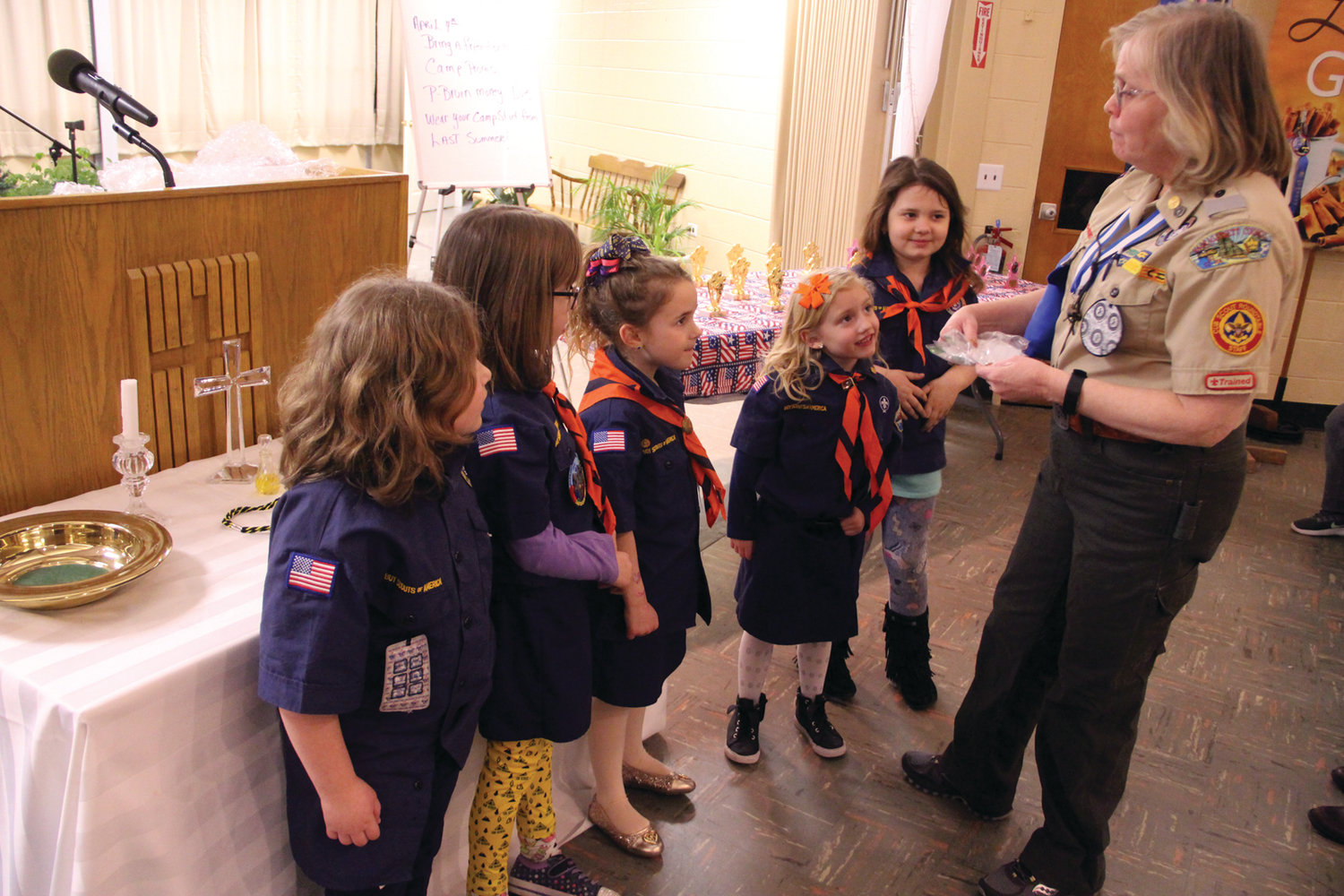 Den Leader Patty Gomm awards badges to members of her Cub Scouts pack.